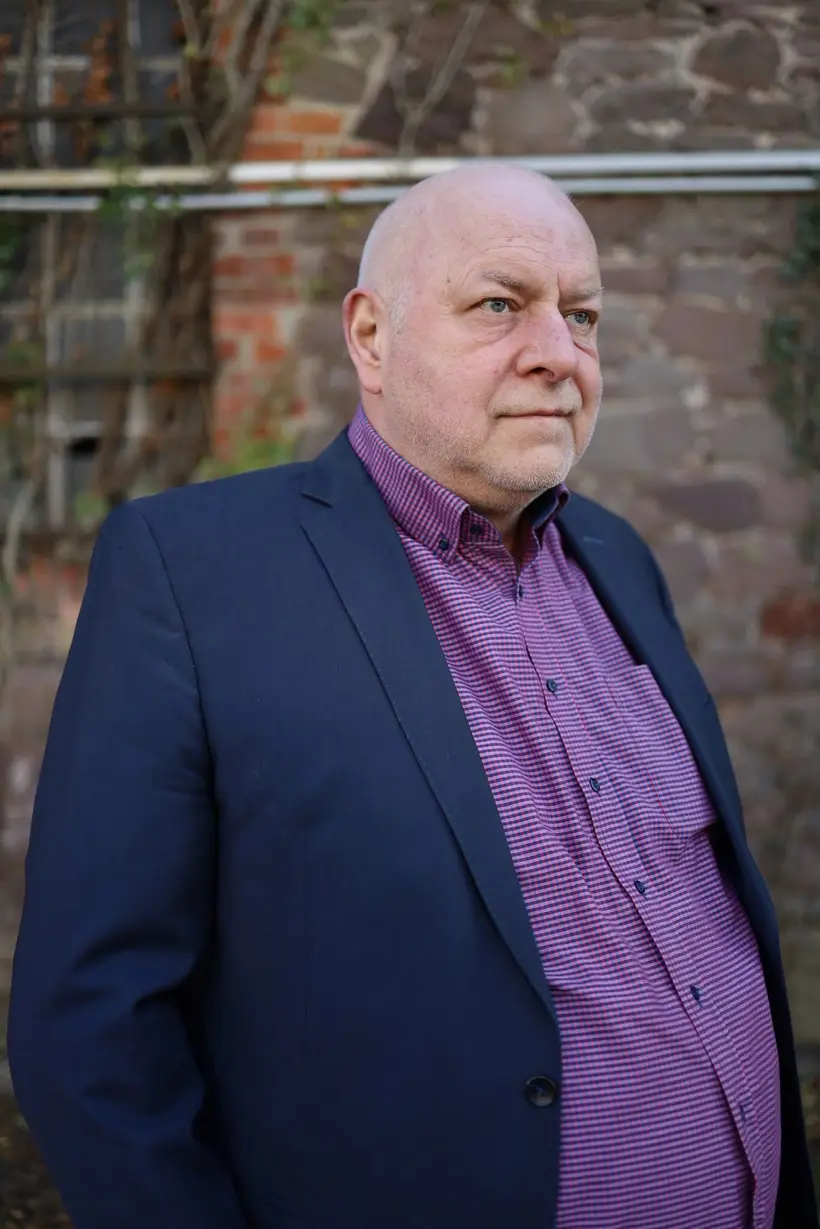 Holger Borchert im Halbprofil vor einer Steinmauer